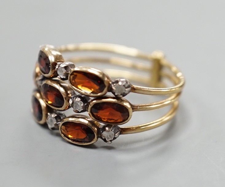 A late Victorian yellow metal, garnet and diamond chip cluster set triple shank ring, size M, gross weight 3.6 grams.